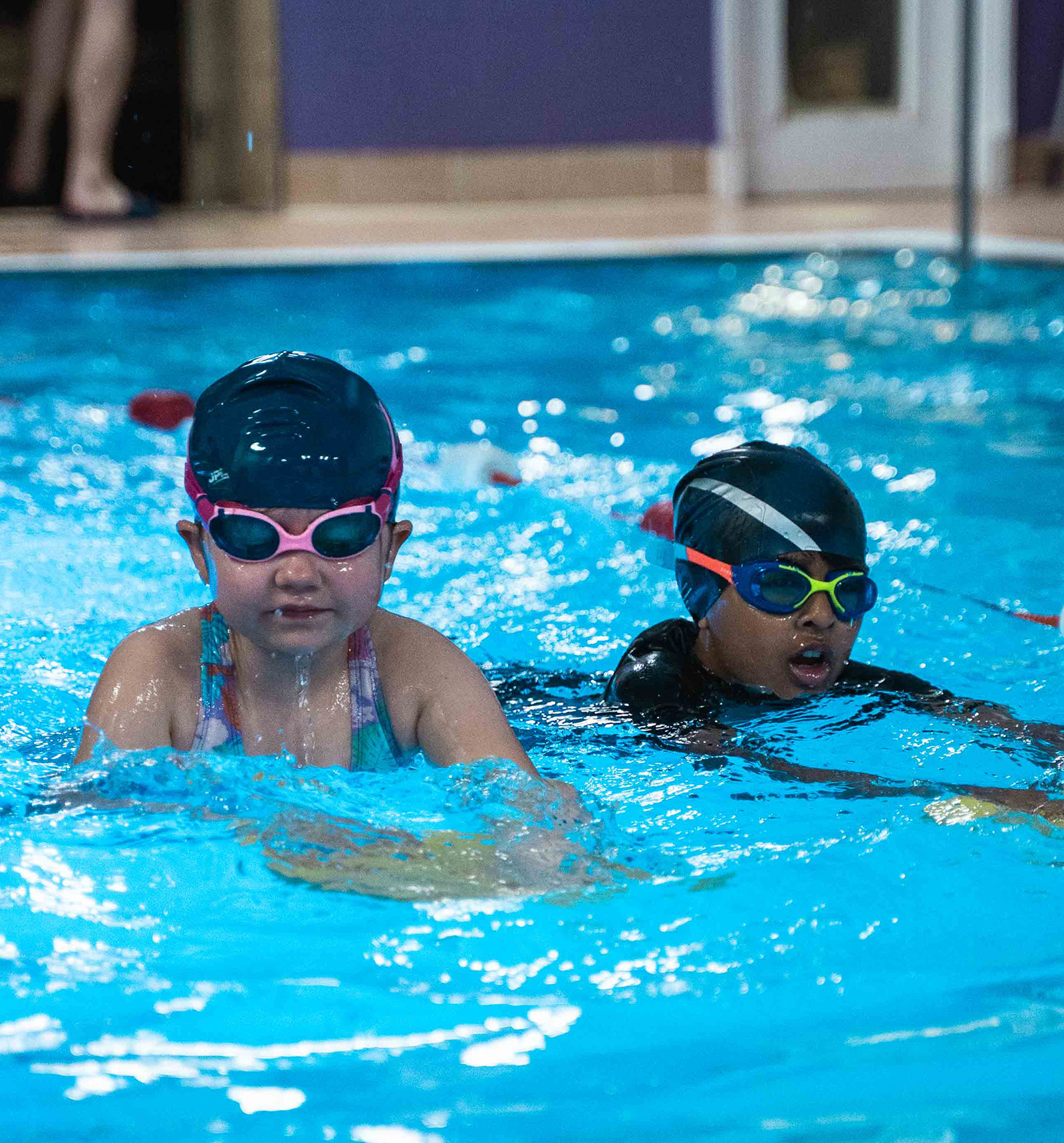 Children sitting by the pool listening to instructions