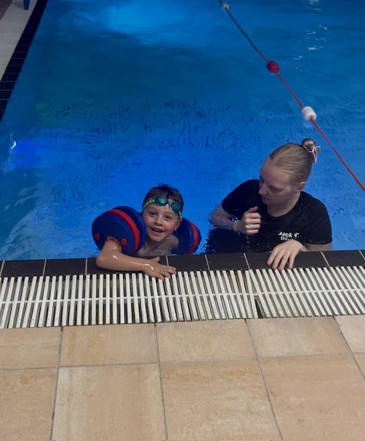 Instructor supporting a young swimmer during an SEN session
