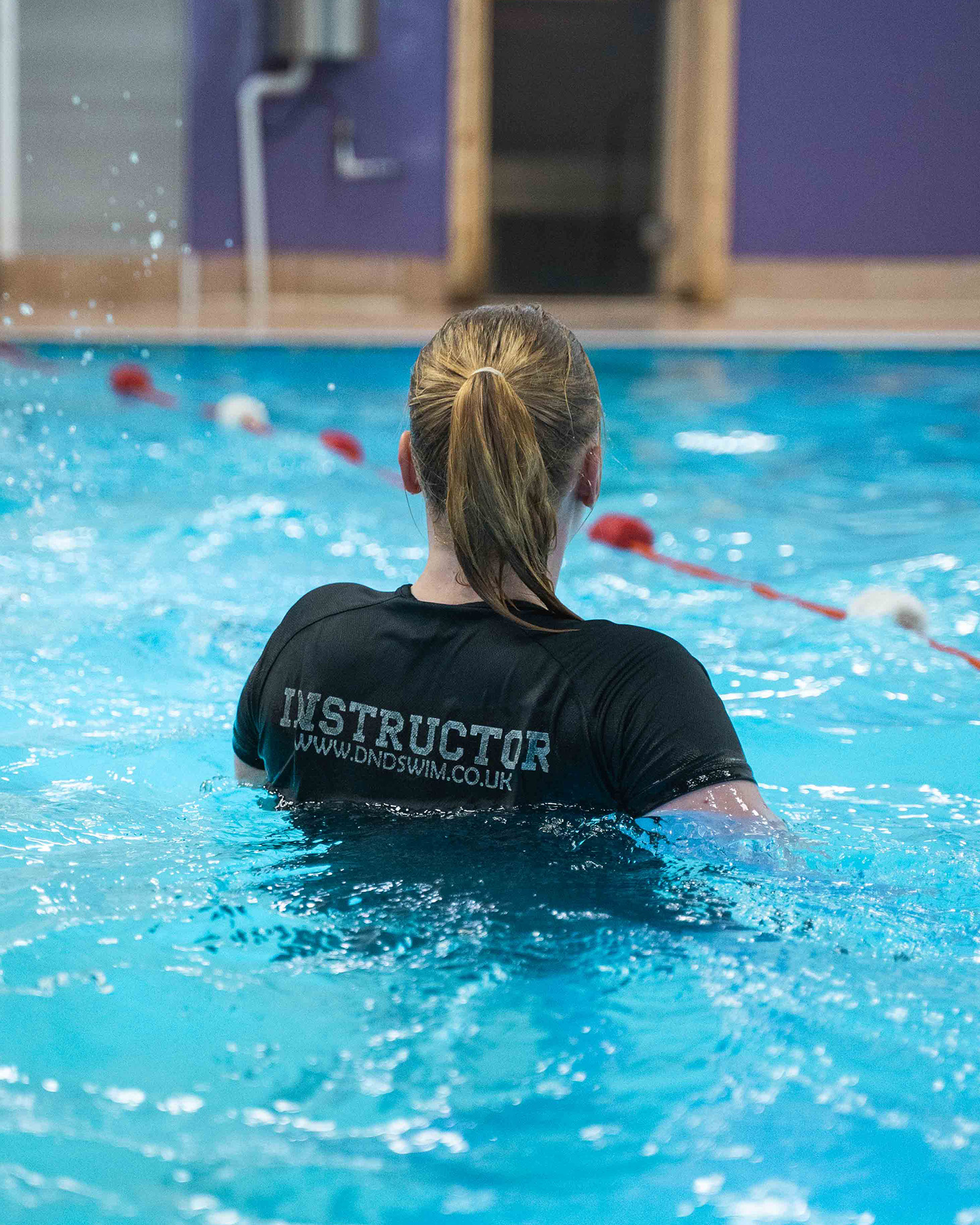 Child learning to swim with an instructor