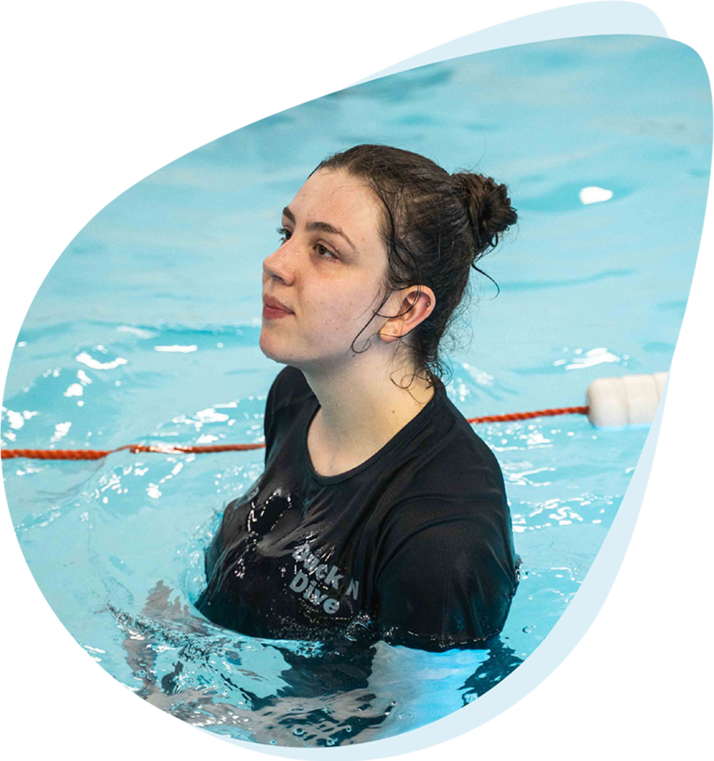 Swimming teacher in the pool encouraging a young child